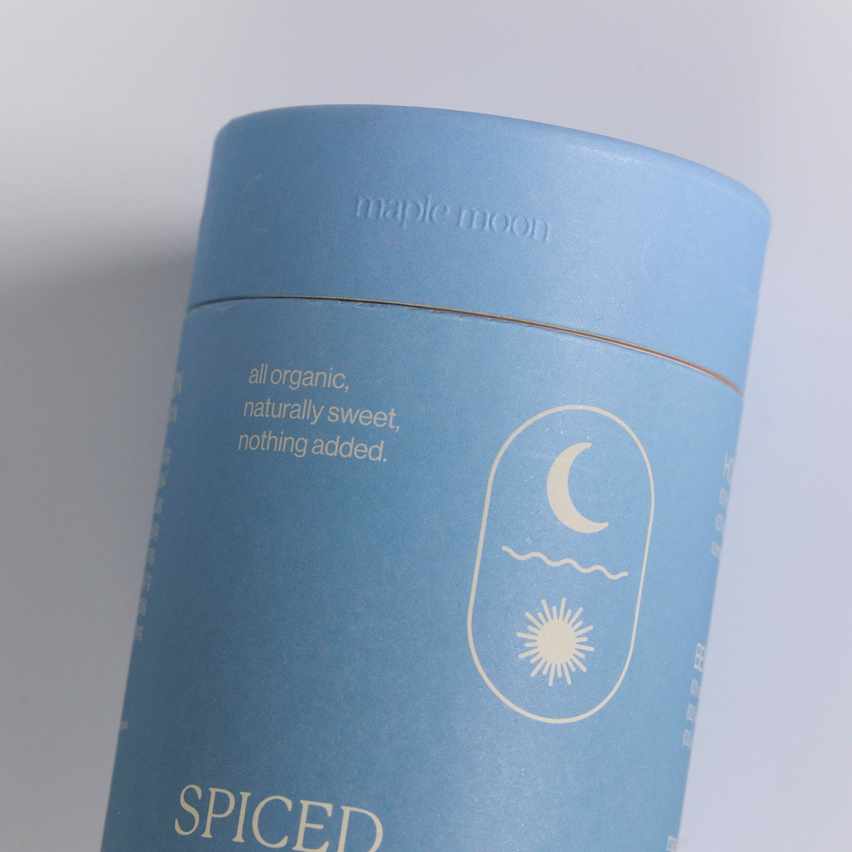 Matte light blue packaging cylinder with lid, featuring custom white text and a celestial moon and sun emblem