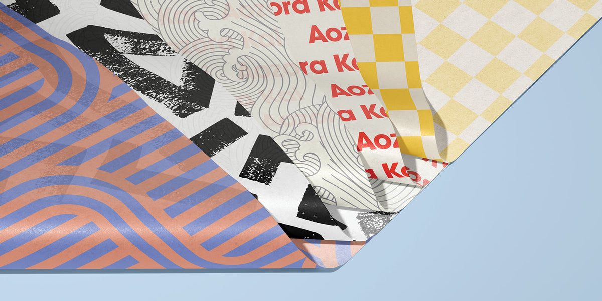 Layered sheets of custom-printed tissue paper featuring geometric, wave, text and yellow chequered patterns