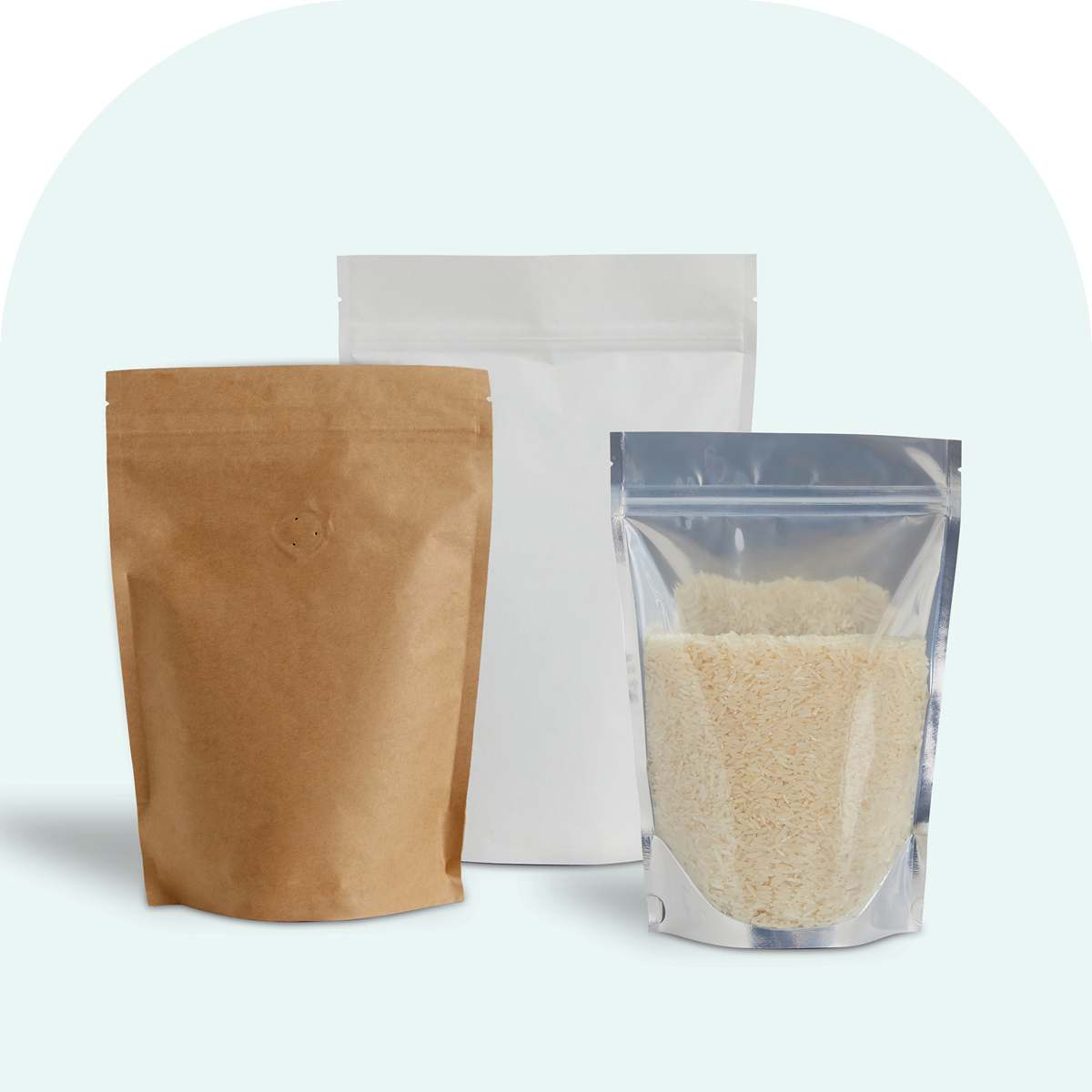 Three plain stand-up pouches in brown kraft, white, and clear plastic filled with rice