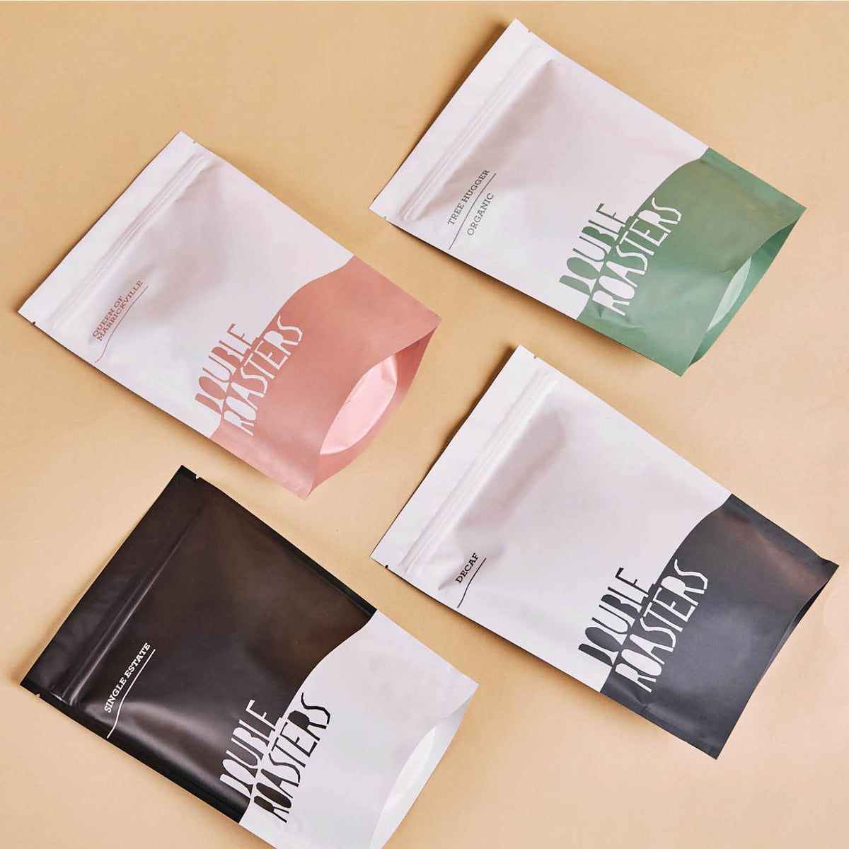 Four custom-printed stand-up pouches in two-tone pink, green, and black designs on a beige background