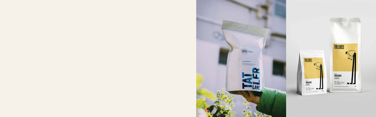 White coffee pouches with custom printed labels, held outdoors and displayed on a plain background