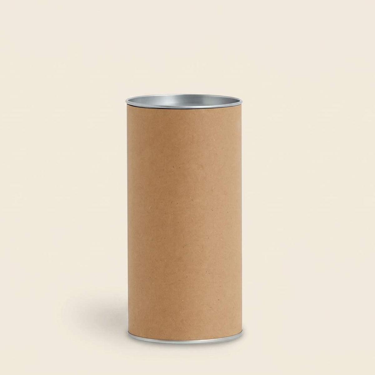 Plain brown kraft packaging cylinder with silver metal rims on a beige background