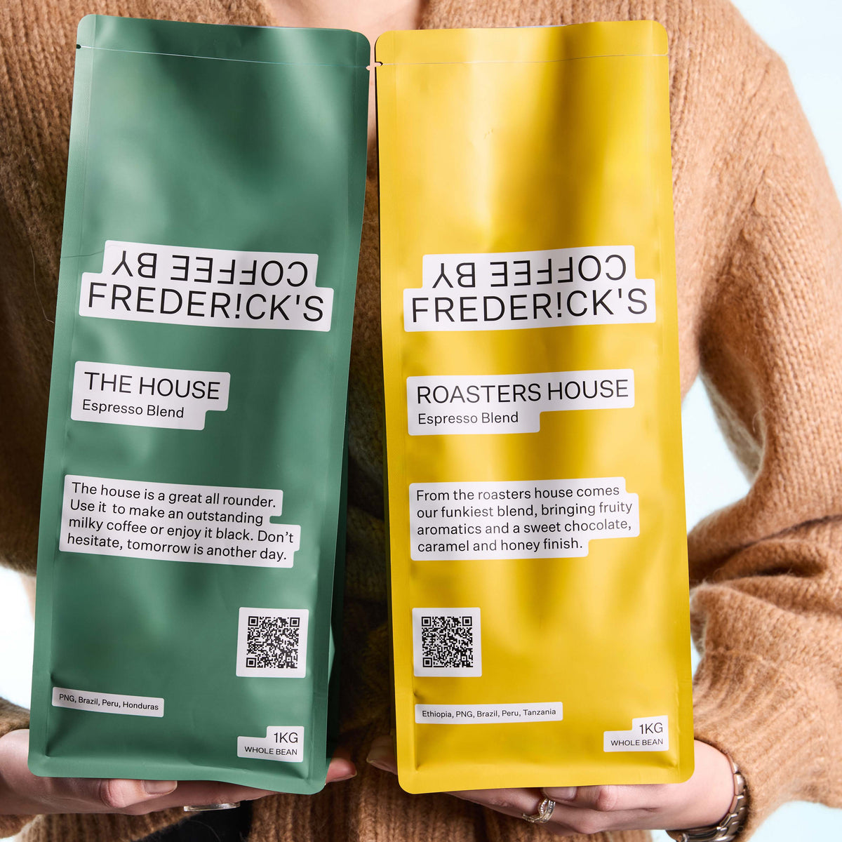 Two custom-printed 1kg matte coffee pouches in green and yellow, held in a person's hands