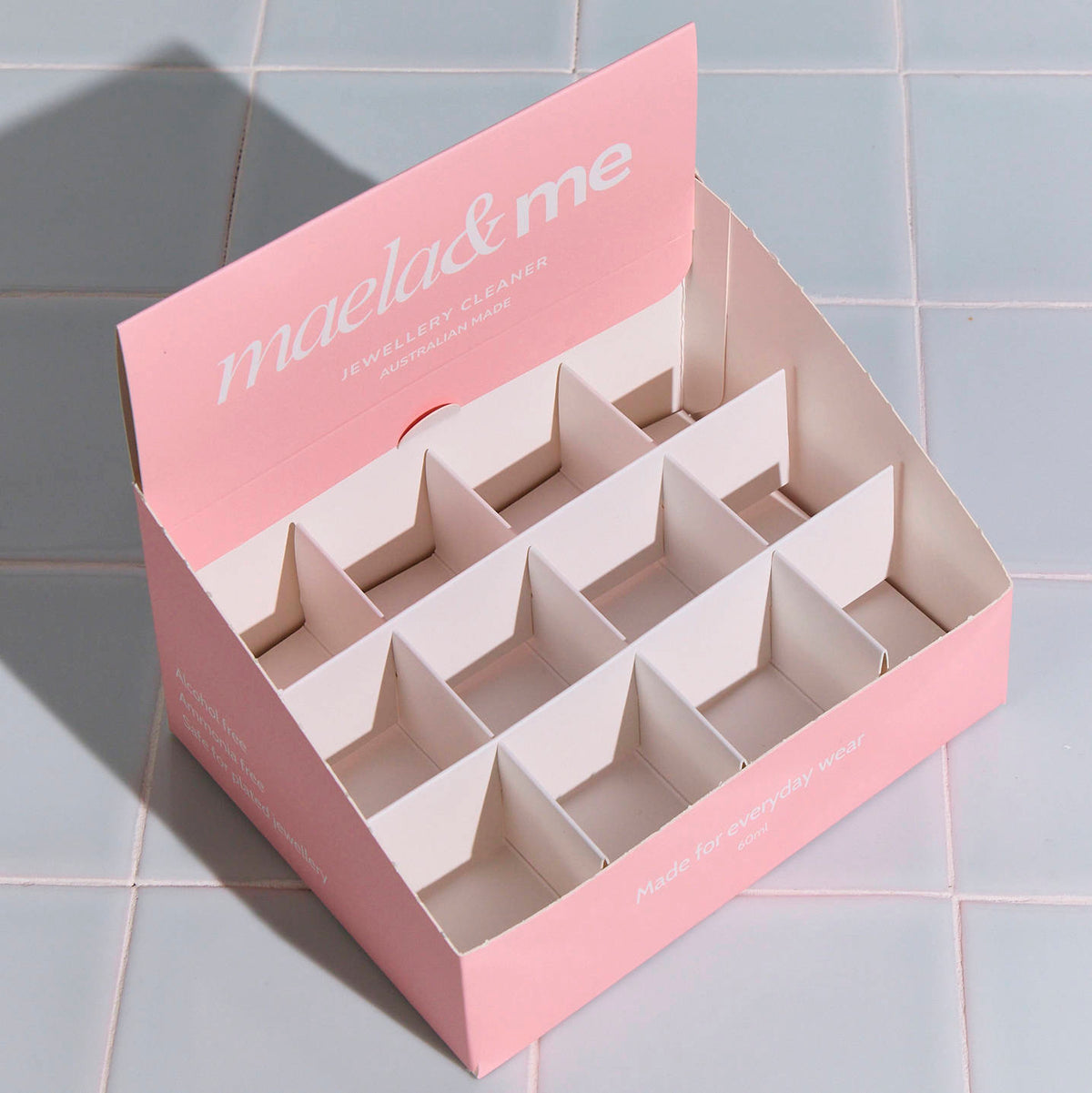 Pink custom counter display box with grid dividers and printed header flap, shown on a light blue tiled surface