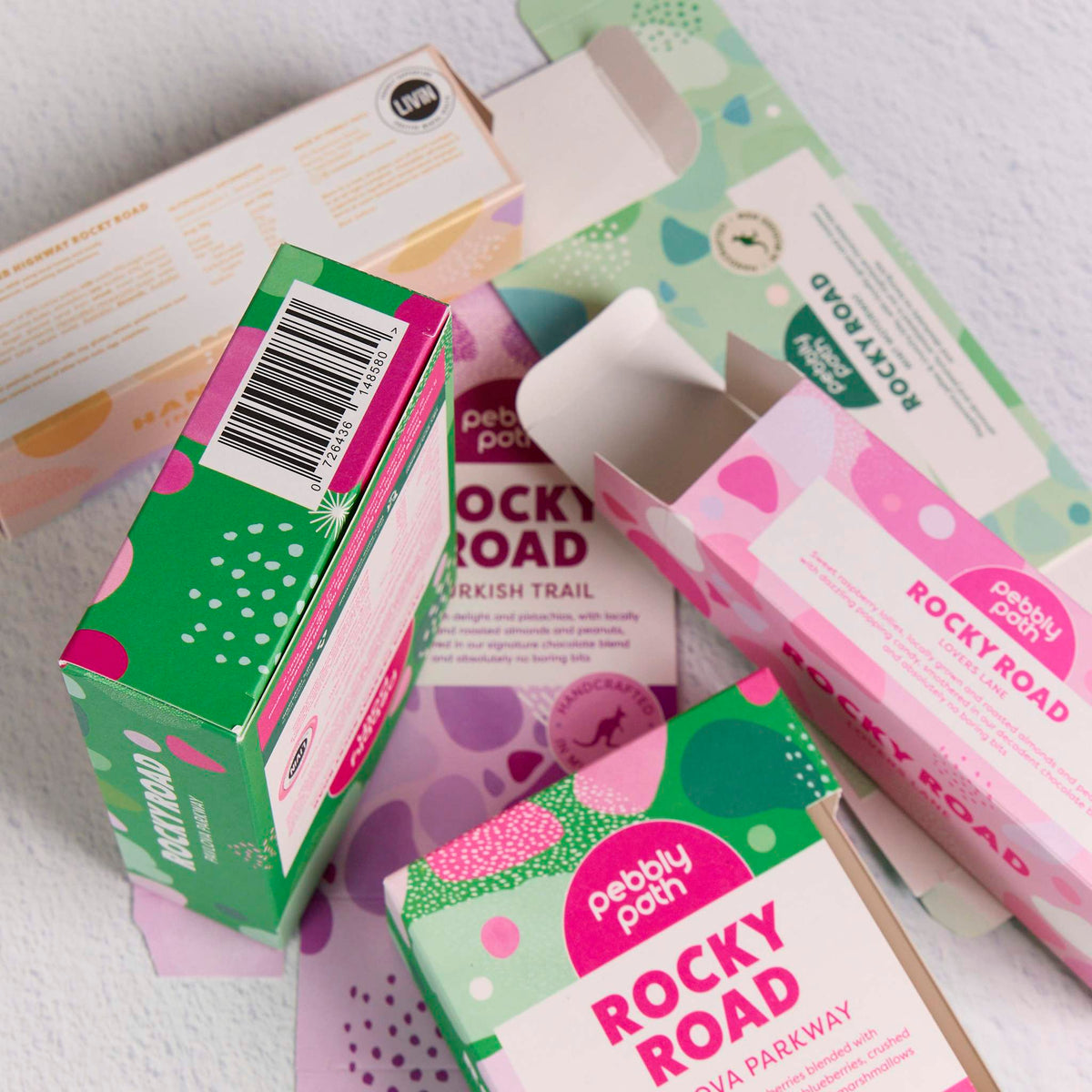 Custom-printed cartons with colourful pink, green and purple patterns, shown both assembled and flat