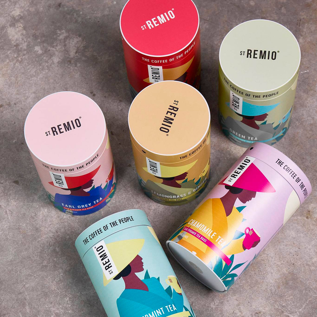 Six custom-printed cylindrical packaging tubes with colourful illustrated tea designs on a grey surface