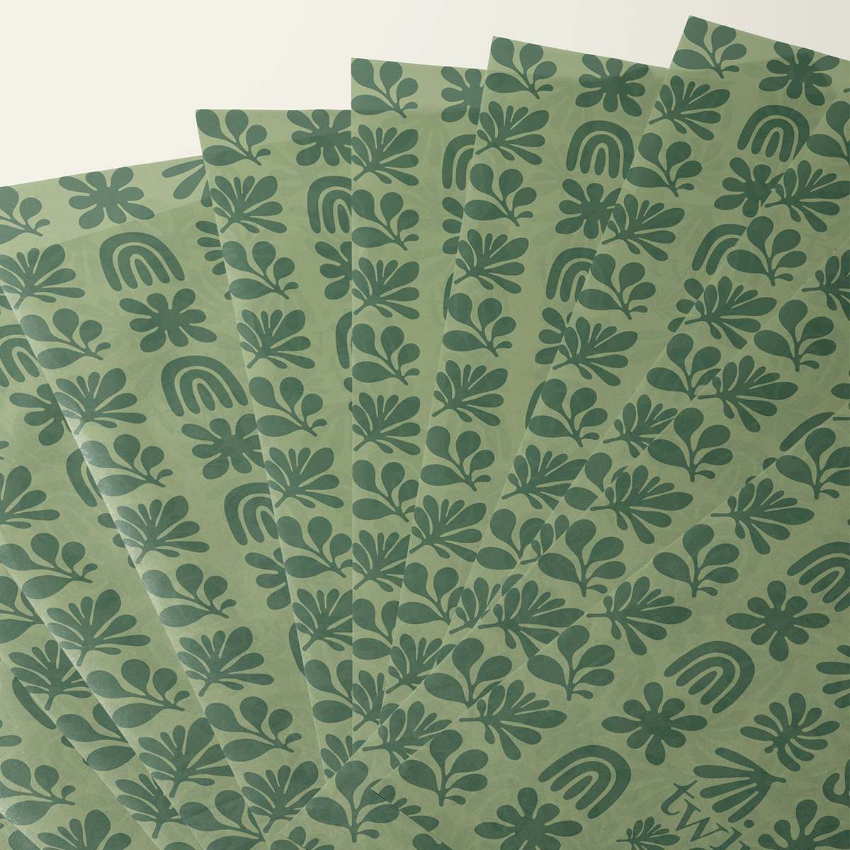 Fanned sheets of sage green tissue paper printed with a dark green abstract botanical pattern