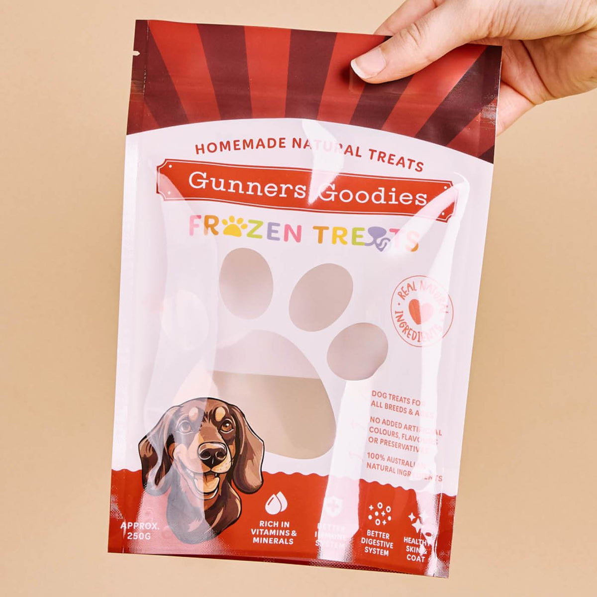 Glossy red and white stand-up pouch with a clear paw-shaped window and dog illustration, held by a hand