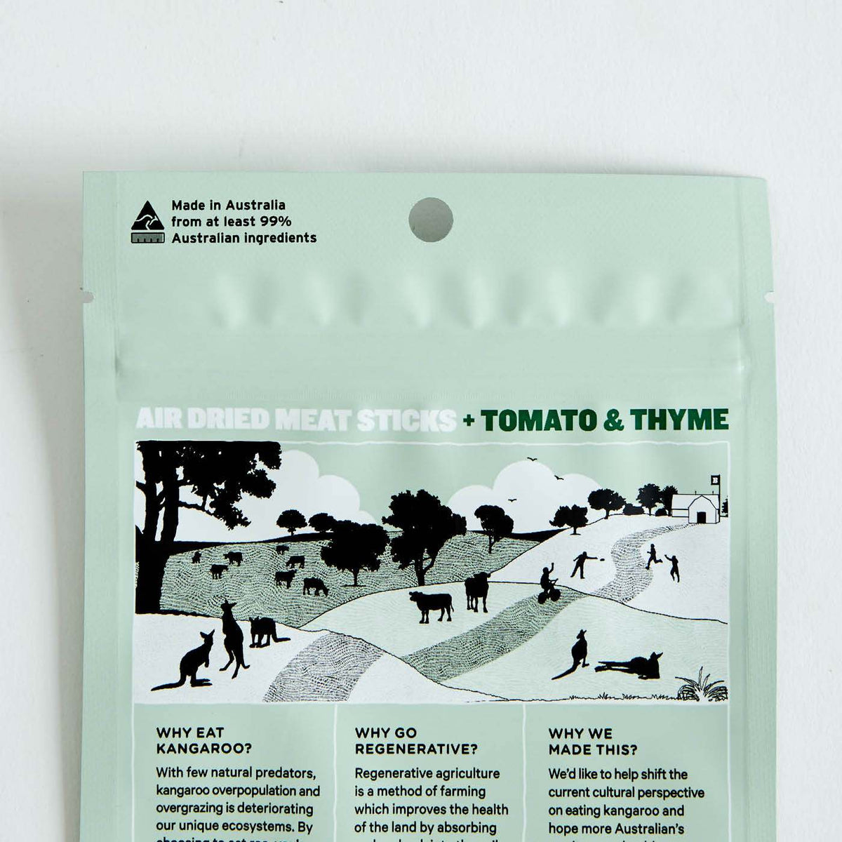 Top of a light green stand-up pouch with a punch hole, printed with a black-and-white landscape illustration