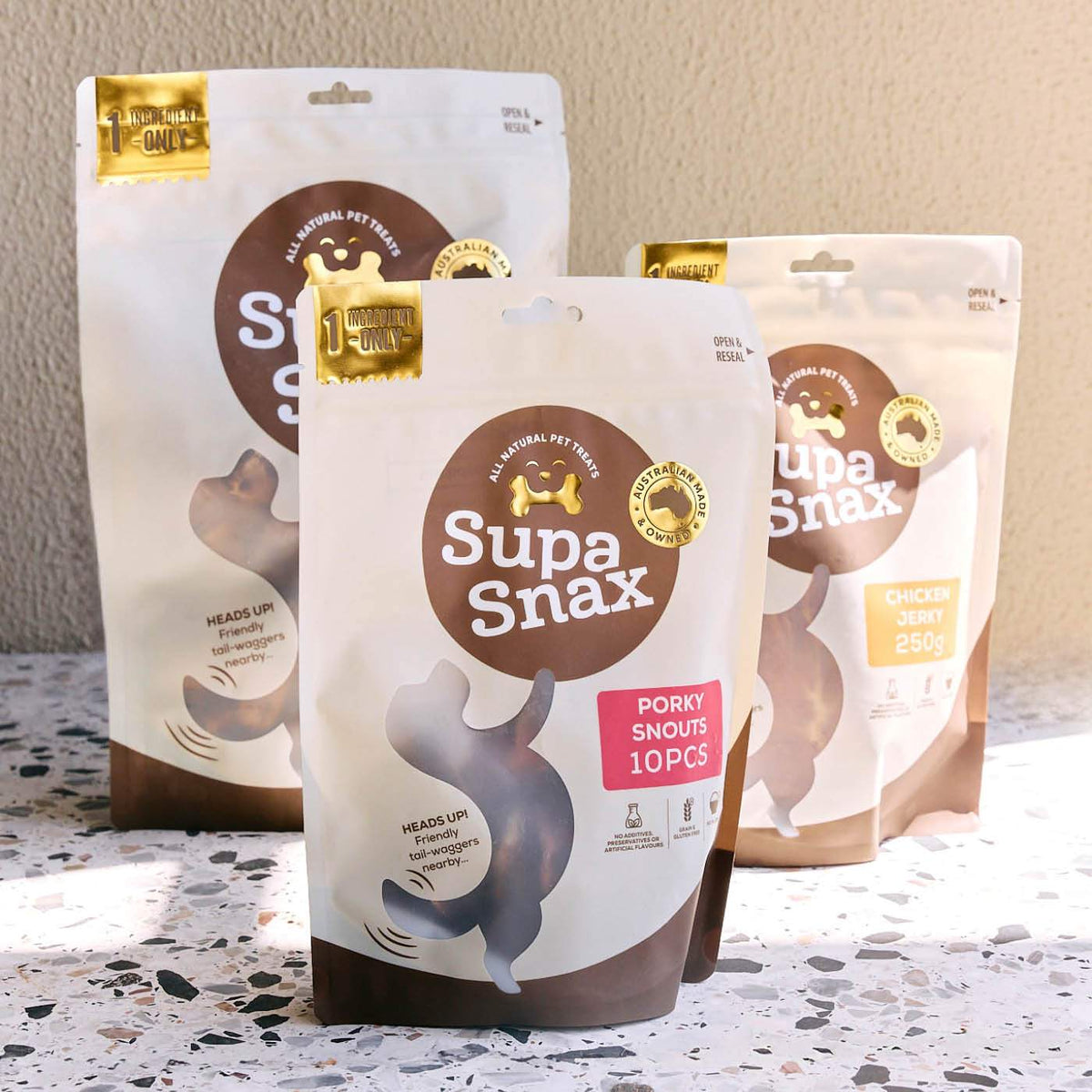 Custom-printed matte stand-up pouches with resealable tops and pet treat branding on a speckled terrazzo surface