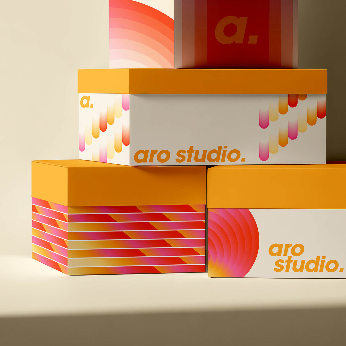 Stacked custom-printed boxes with yellow lids, colourful pink and orange geometric patterns, and aro studio text