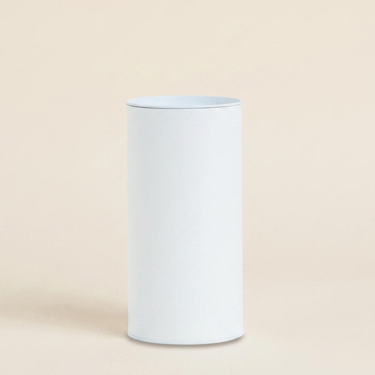 Plain white packaging cylinder with a lid on a light beige background