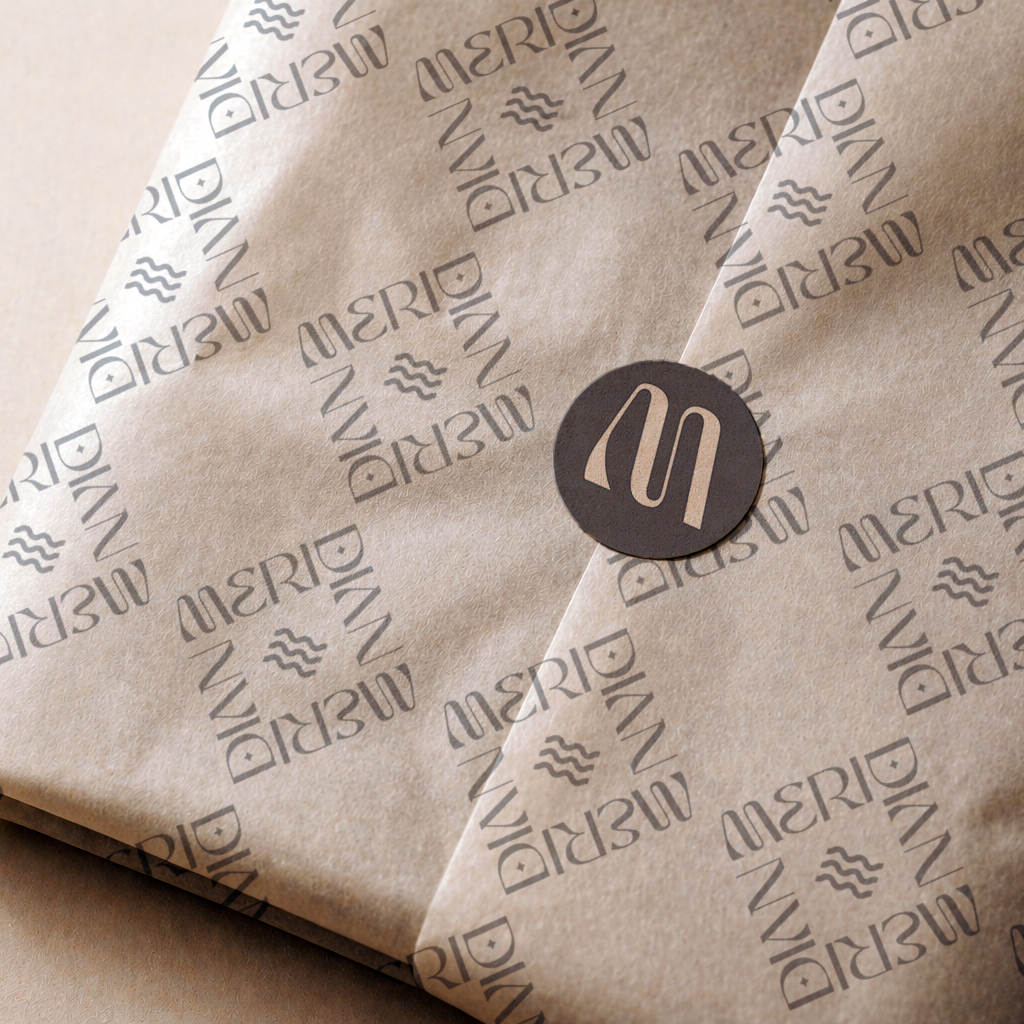 Round dark brown paper sticker with a logo sealing folded kraft paper printed with a repeating design