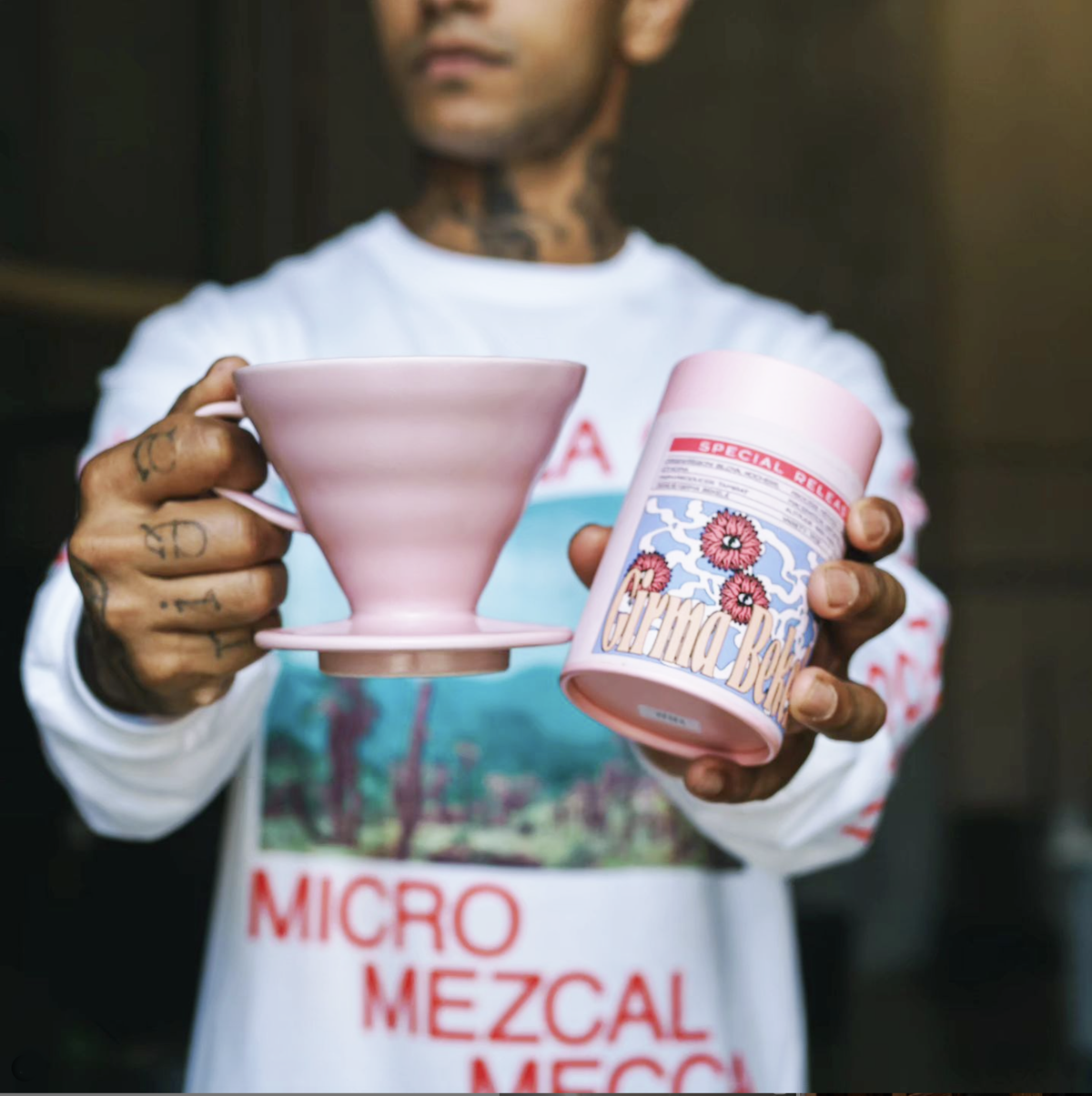 A person holding a pink ceramic coffee dripper and a custom-printed pink packaging cylinder